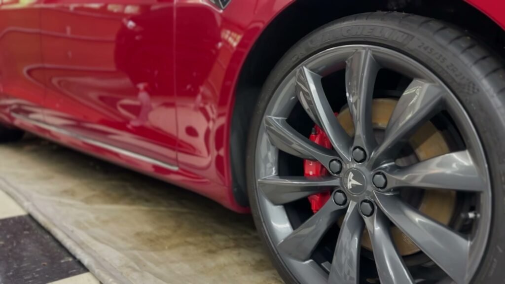 exterior detailing of red tesla showing ceramic coated rim and glossy paint